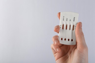 Photo of Woman holding disposable multi-infection express test on light background, closeup. Space for text