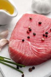 Photo of Raw tuna fillet and spices on light table, closeup