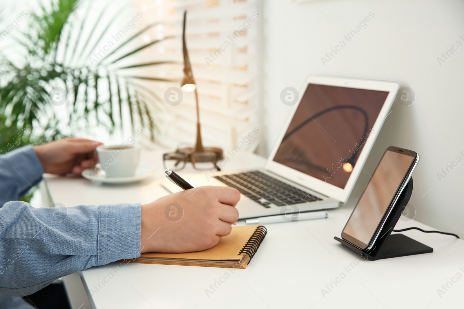 Photo of Man working at table while his mobile phone charging with wireless device