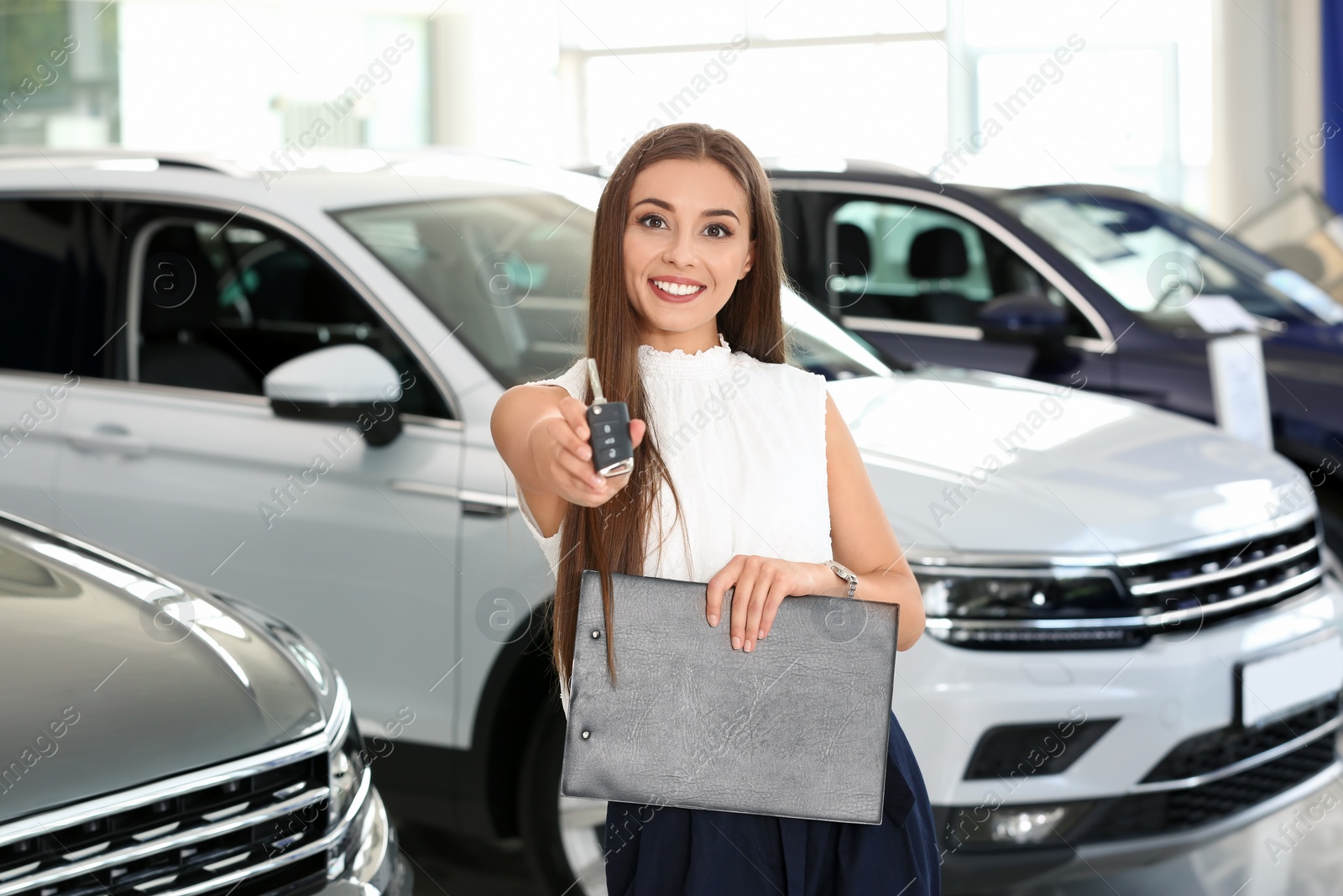 Photo of Saleswoman with car key standing in salon