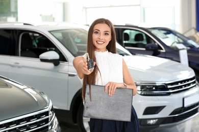 Photo of Saleswoman with car key standing in salon