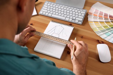Photo of Man with sketchbook, pencil and ruler at wooden table, closeup