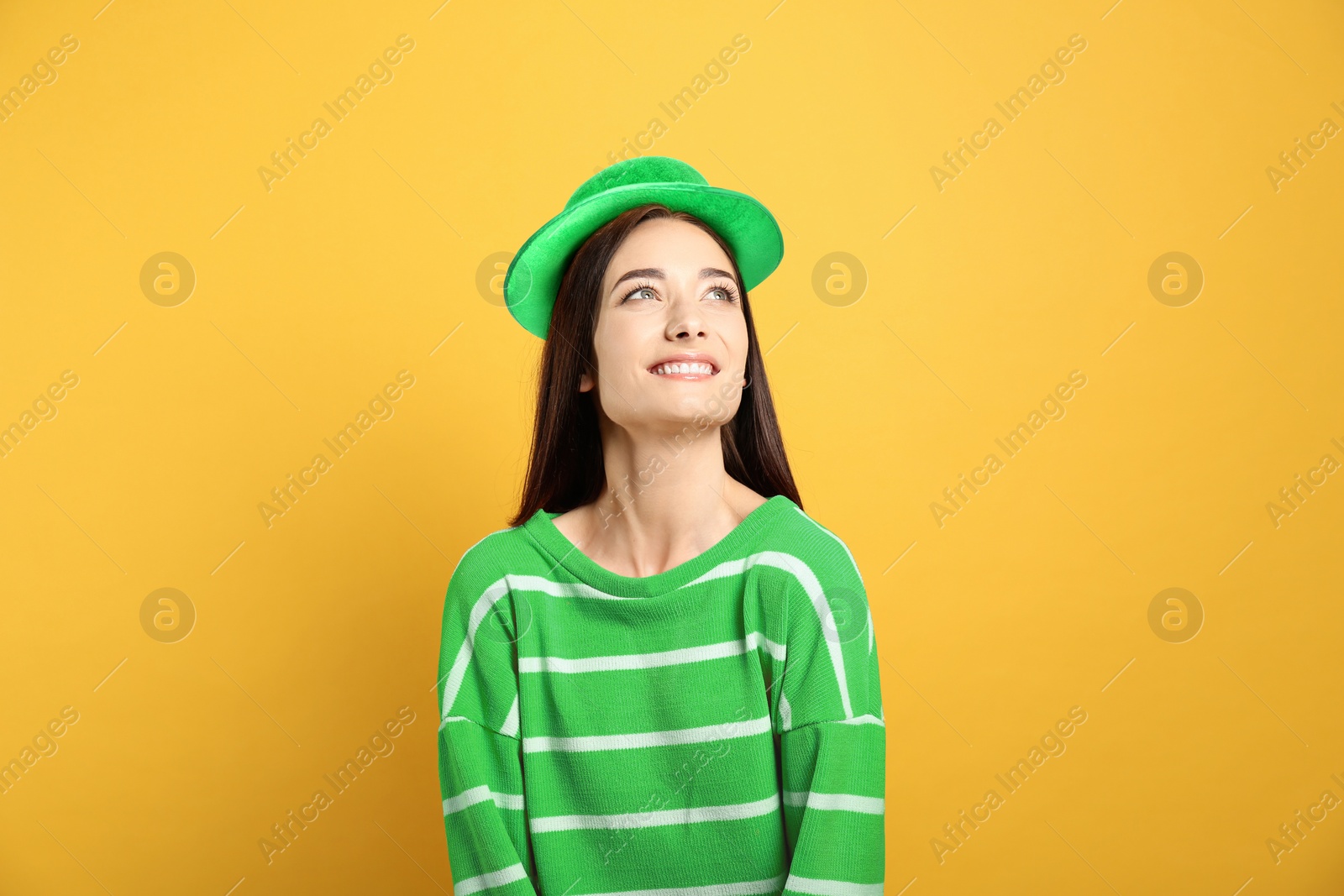 Image of St. Patrick's day party. Pretty woman in green leprechaun hat on golden background