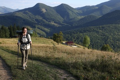 Tourist with backpack and trekking poles hiking through mountains, space for text