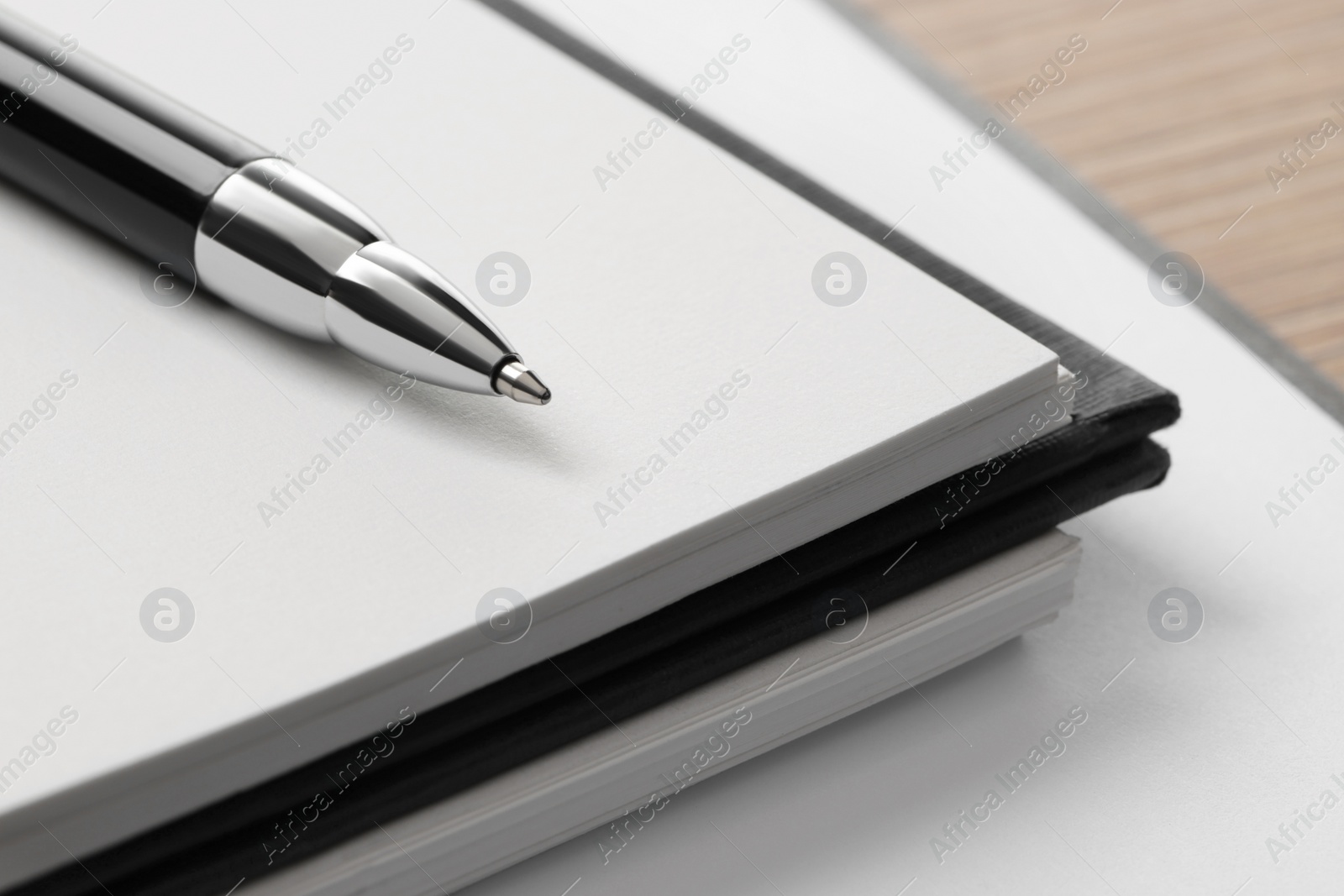 Photo of Ballpoint pen and notebooks on wooden table, closeup