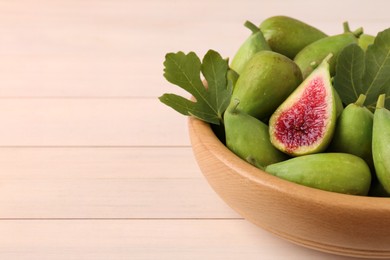 Cut and whole fresh green figs on white wooden table, closeup. Space for text