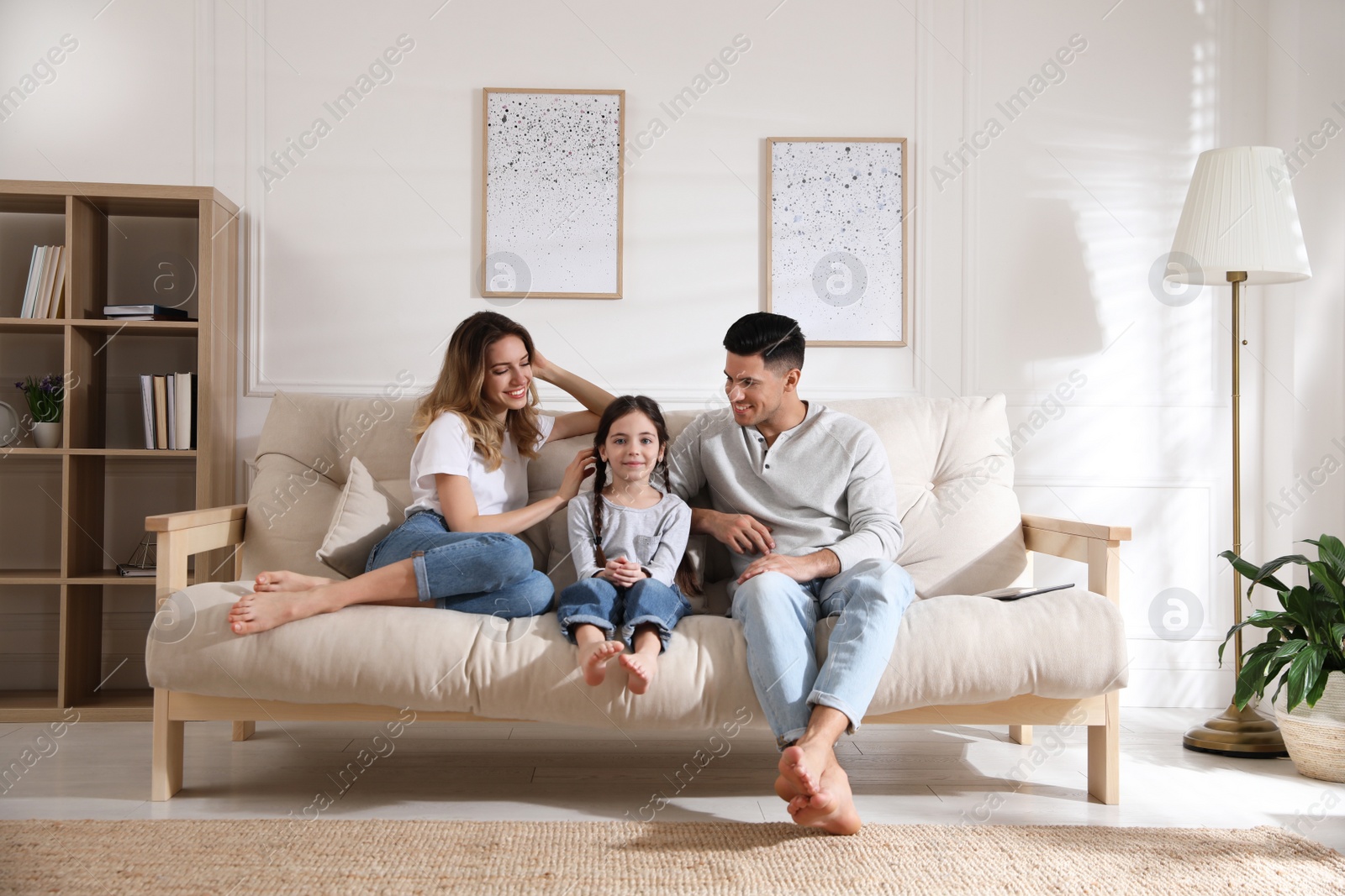 Photo of Happy family with little daughter sitting on sofa in living room