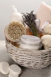 Photo of Spa gift set of different luxury products in wicker basket on grey table, closeup