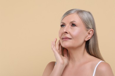 Portrait of beautiful senior woman on beige background. Space for text