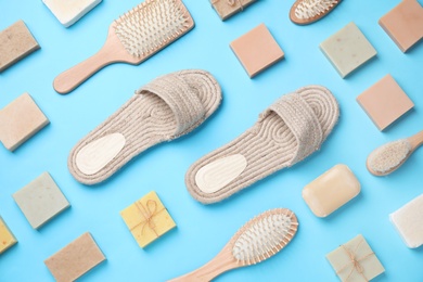 Slippers, hair brushes and soap bars on light blue background, flat lay