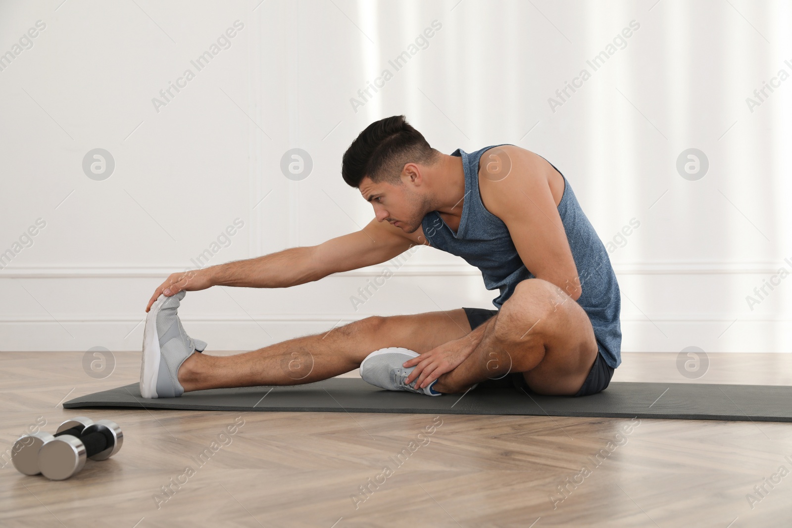 Photo of Handsome man stretching on yoga mat indoors