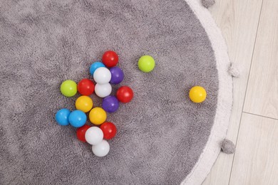 Photo of Bright toy balls and soft rug on floor in kindergarten, top view
