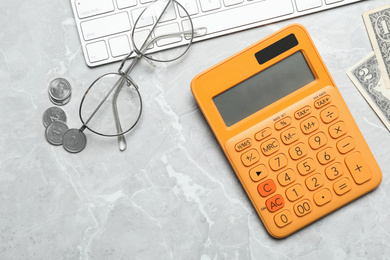 Photo of Calculator, glasses, keyboard and money on marble table, flat lay. Tax accounting