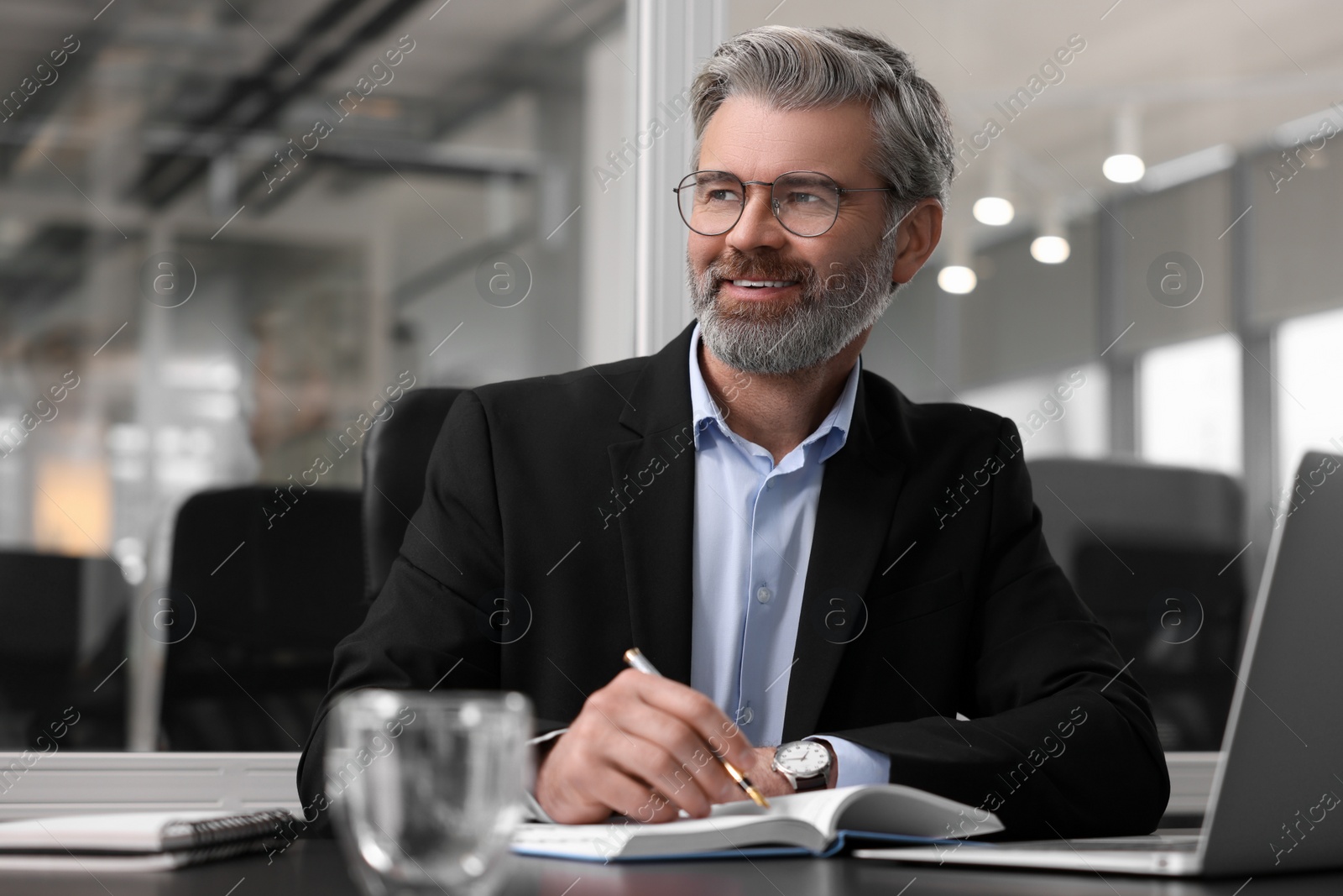 Photo of Smiling man at table in office. Lawyer, businessman, accountant or manager