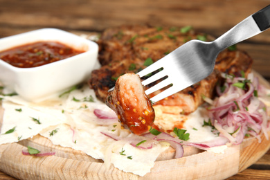 Photo of Fork with piece of delicious grilled meat, closeup