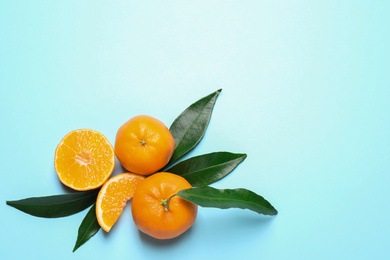 Flat lay composition with fresh ripe tangerines and leaves on light blue background. Citrus fruit