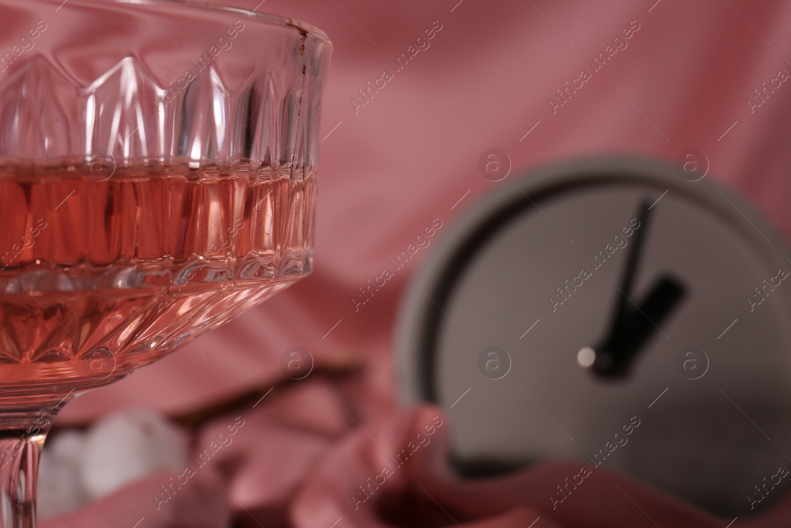 Photo of Glass of alcohol drink on pink cloth, closeup. Space for text