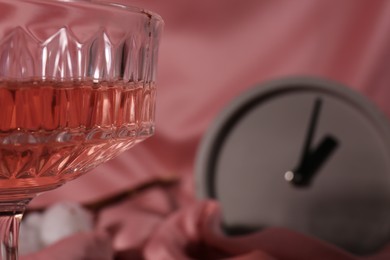 Photo of Glass of alcohol drink on pink cloth, closeup. Space for text