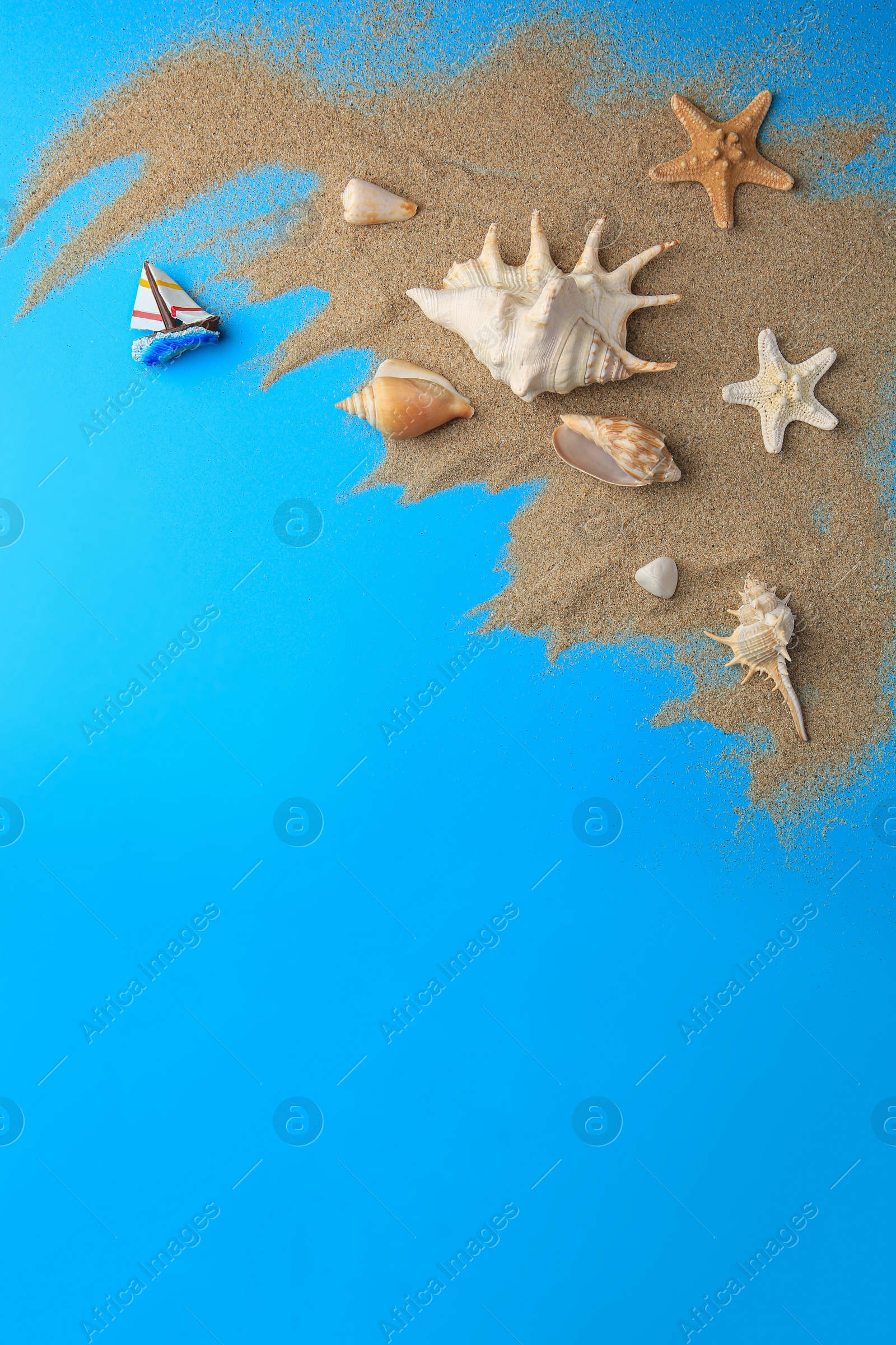 Photo of Flat lay composition with beautiful starfishes and sand on blue background. Space for text