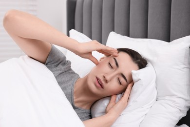 Photo of Sad woman suffering from headache in bed indoors