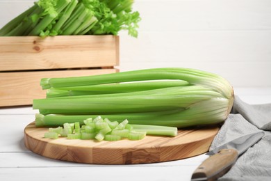 Board with fresh cut and whole celery on white wooden table