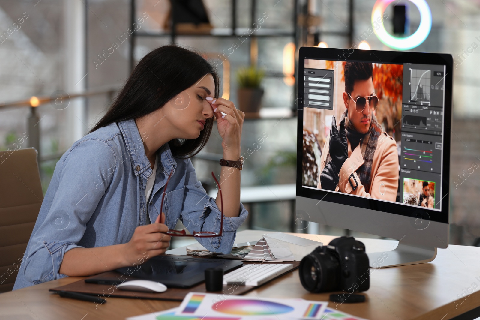 Photo of Tired retoucher at table with modern computer in office