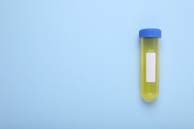 Photo of Test tube with liquid on light blue background, top view and space for text. Kids chemical experiment toy