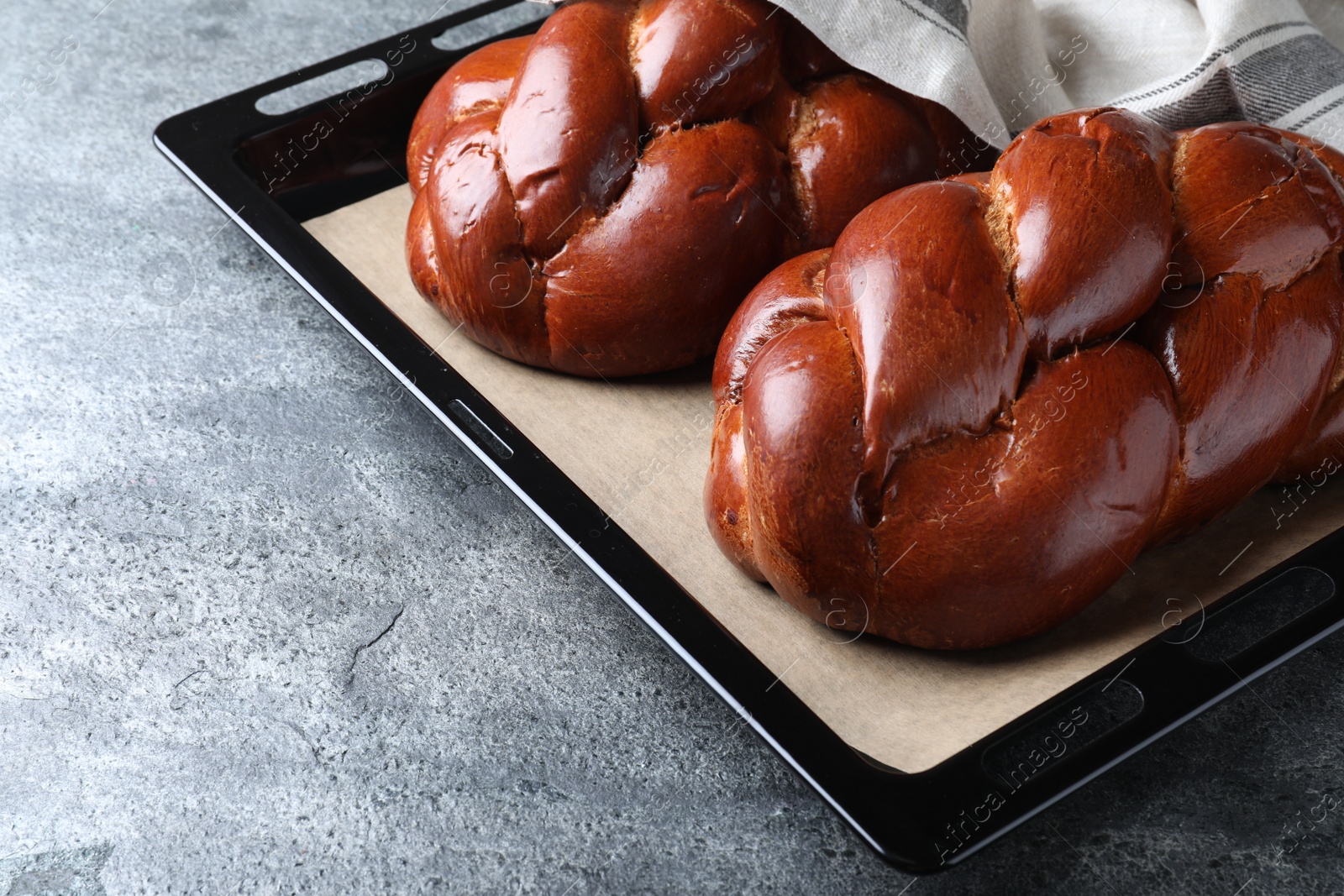 Photo of Homemade braided bread on grey table, closeup. Traditional challah