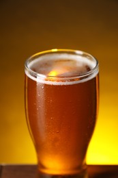 Photo of Glass with fresh beer on table against dark background, closeup