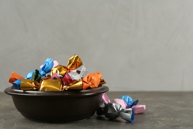 Photo of Candies in colorful wrappers on grey table, space for text