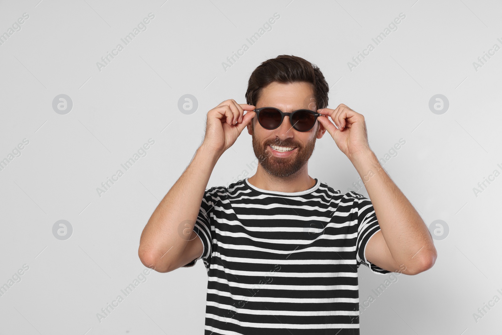 Photo of Portrait of smiling bearded man with stylish sunglasses on grey background