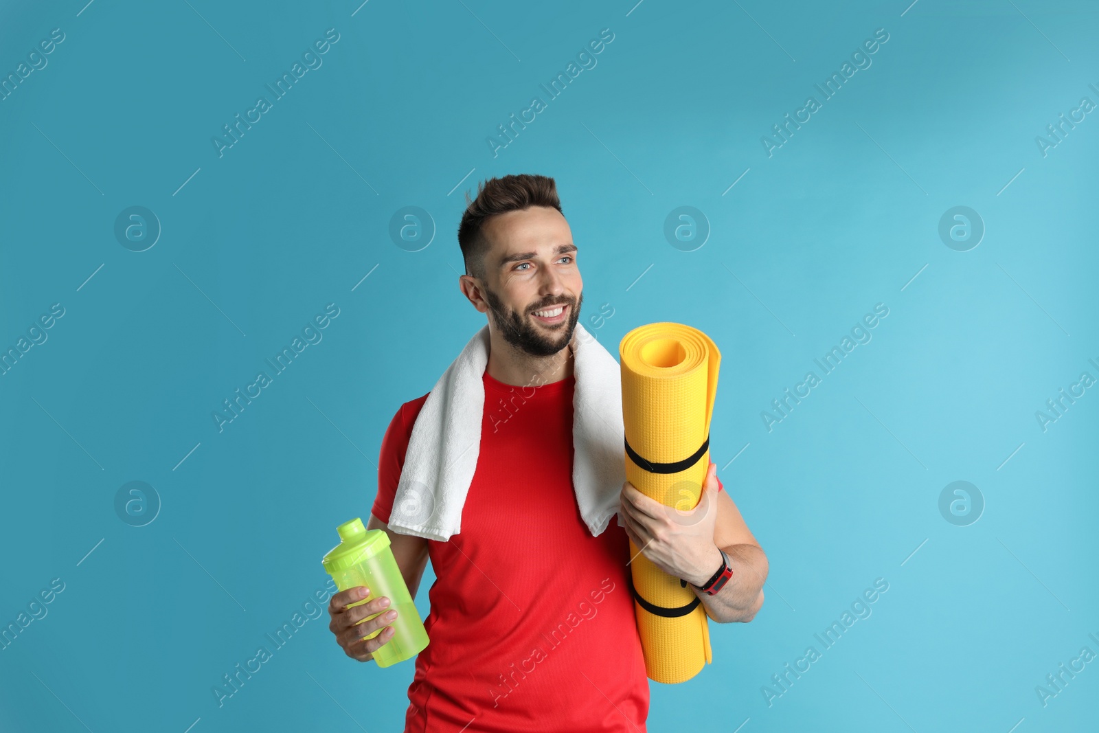 Photo of Beautiful man with yoga mat, towel and shaker on turquoise background