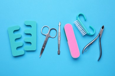 Set of pedicure tools on light blue background, flat lay