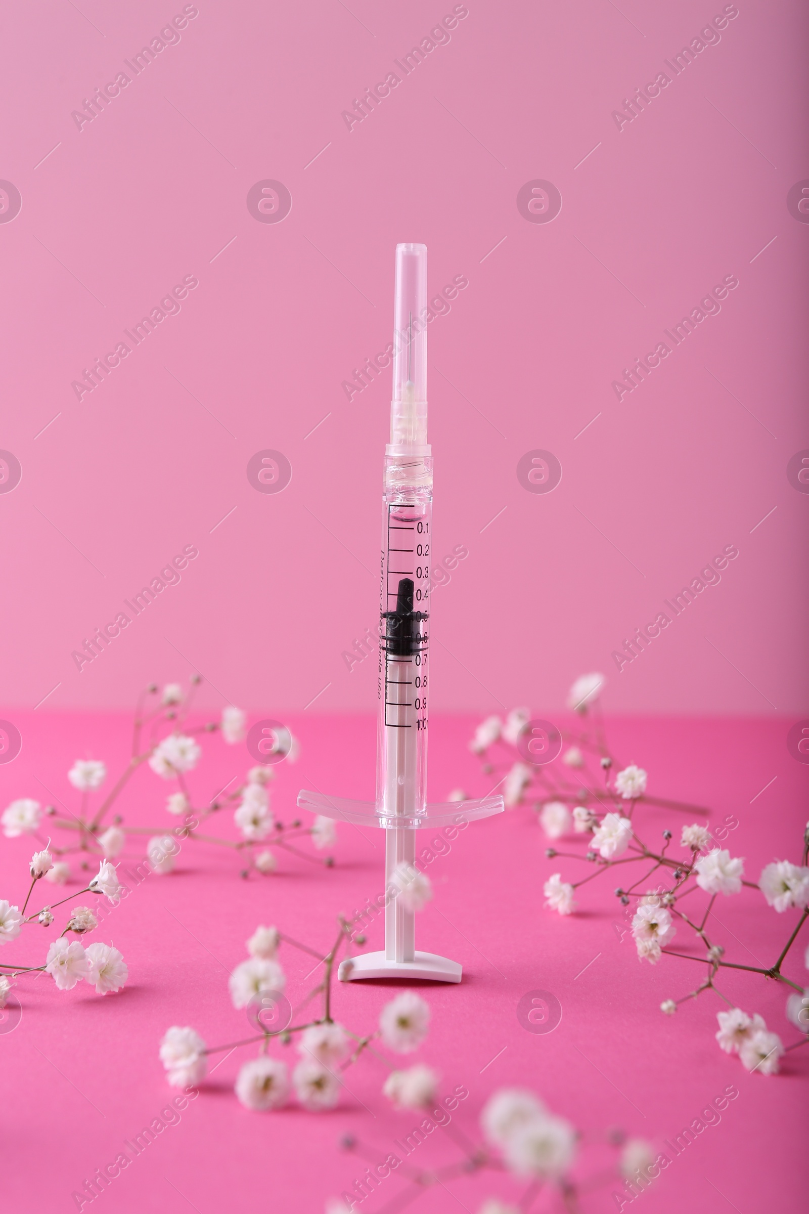 Photo of Cosmetology. Medical syringe and gypsophila flowers on pink background