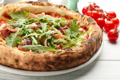 Tasty pizza with meat and arugula on white wooden table, closeup