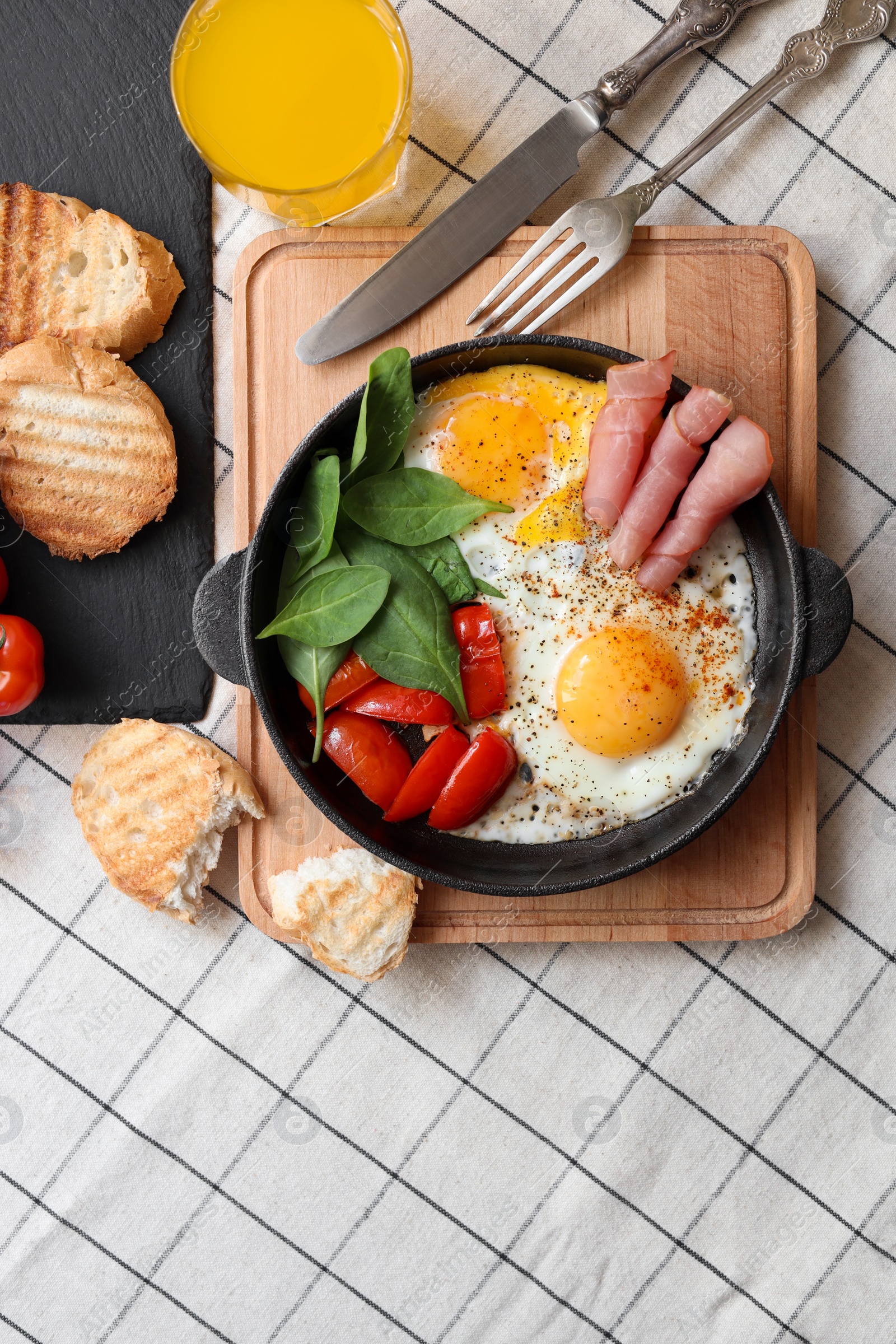 Photo of Delicious fried eggs with spinach, tomatoes and ham served on table, flat lay