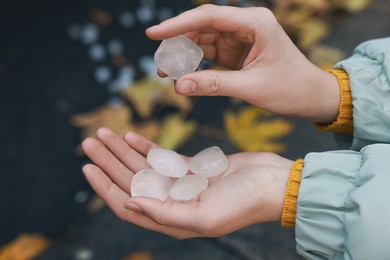 Photo of Woman holding hail grains after thunderstorm outdoors, closeup