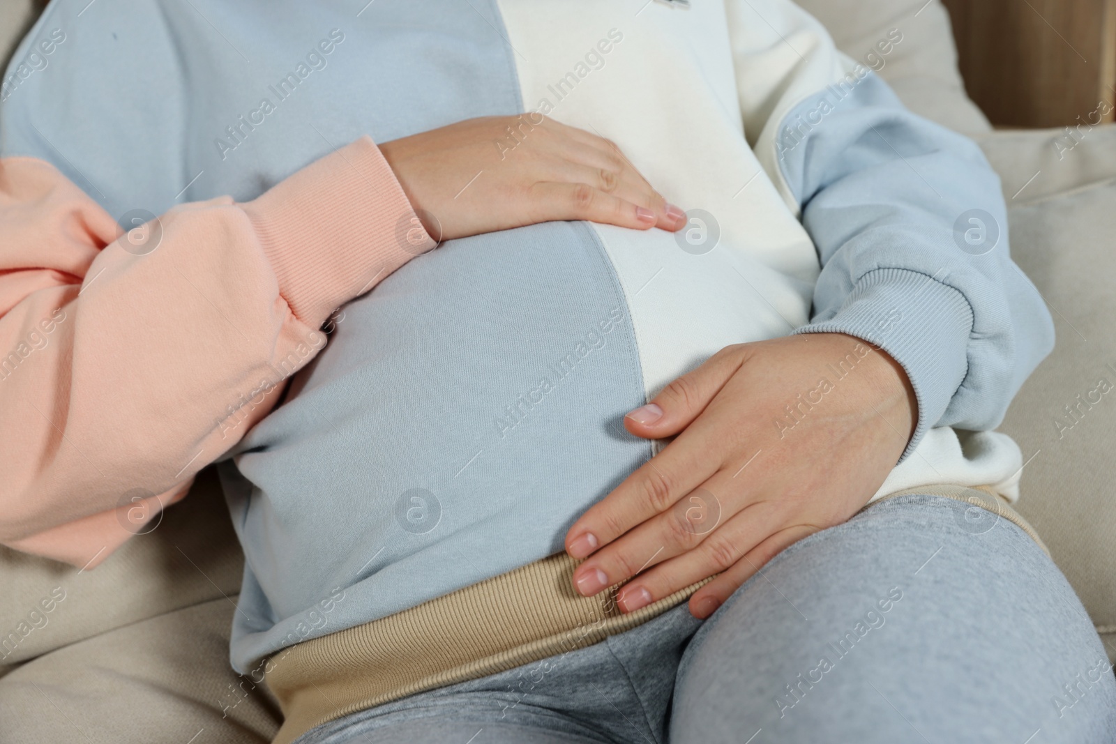 Photo of Pregnant woman touching belly indoors, closeup view