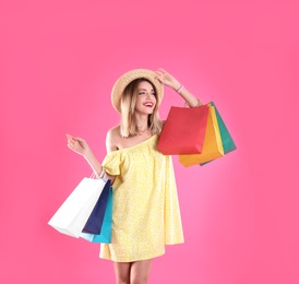 Photo of Beautiful young woman with shopping bags on color background