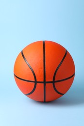 Photo of One orange basketball ball on light blue background