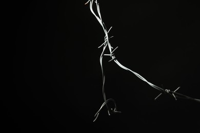 Photo of Metal barbed wire on black background. Space for text