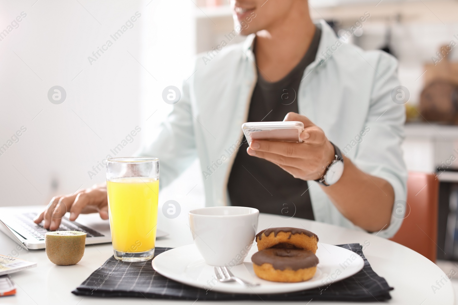 Photo of Food blogger with laptop and smartphone at table indoors, closeup