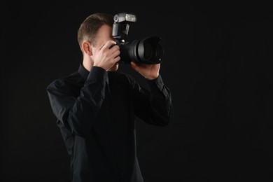 Professional photographer taking picture on black background, space for text