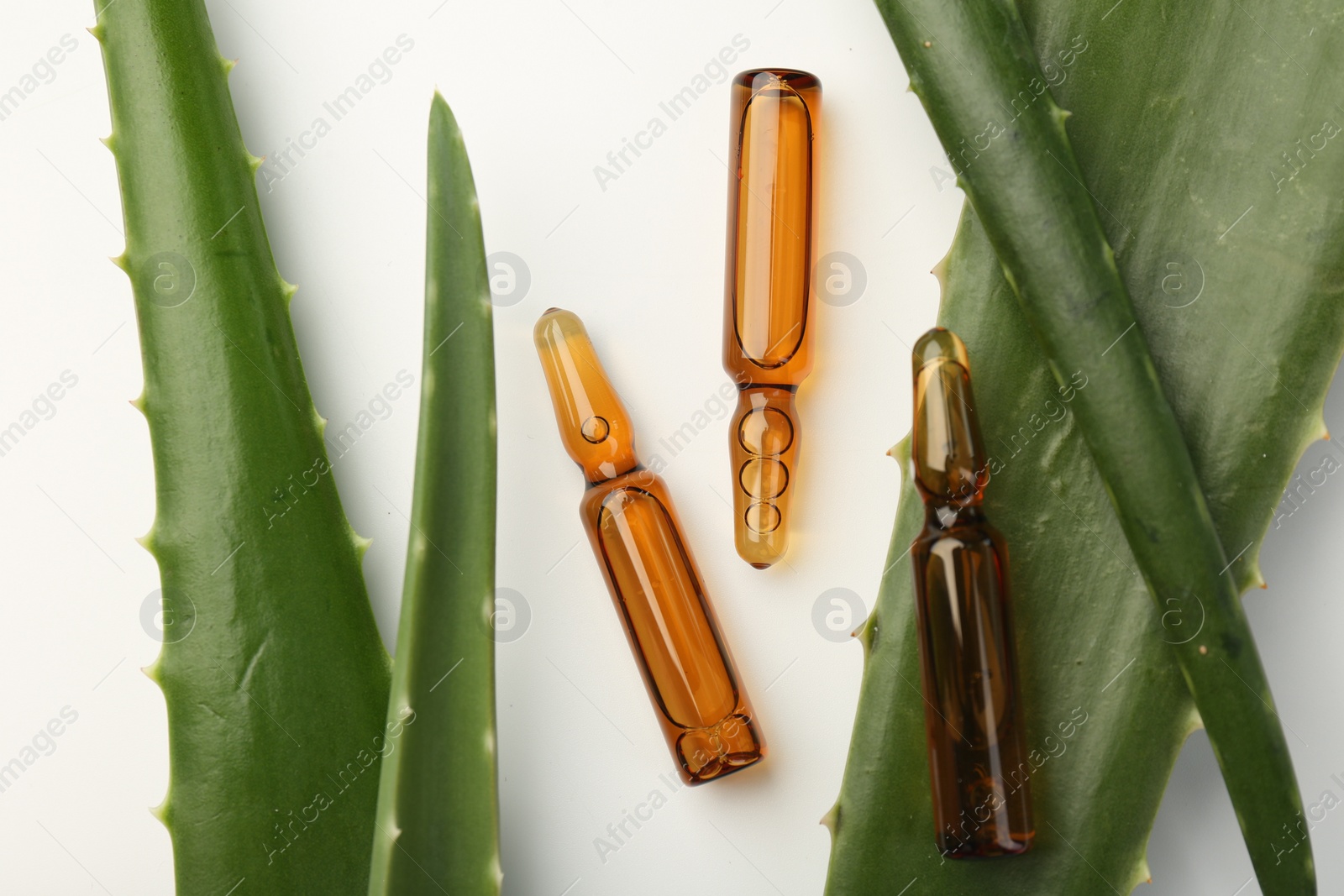 Photo of Skincare ampoules and aloe leaves on white background, flat lay