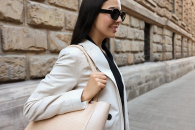 Photo of Young woman with stylish bag on city street, closeup