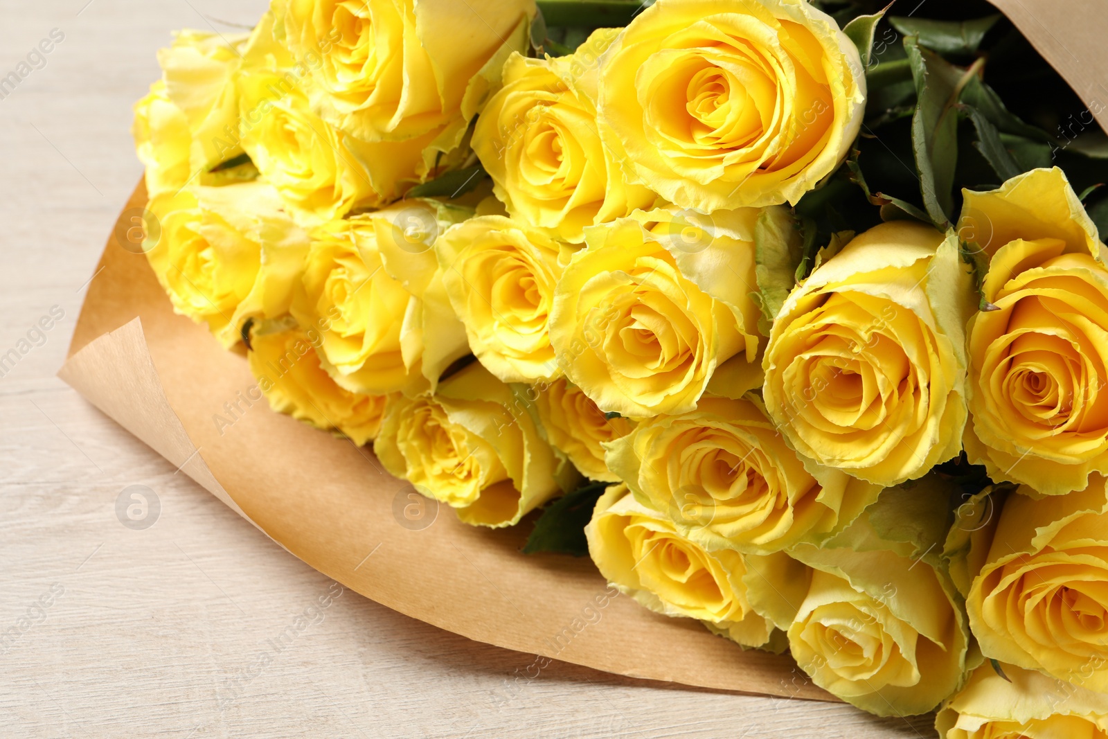 Photo of Beautiful bouquet of yellow roses on wooden table, closeup