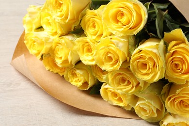 Photo of Beautiful bouquet of yellow roses on wooden table, closeup