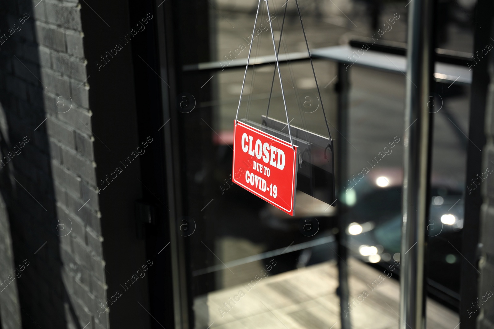 Photo of Red sign with text Closed Due To Covid-19 hanging on glass door. Coronavirus quarantine