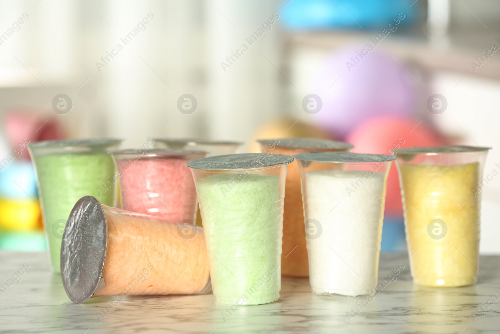 Photo of Plastic cups with cotton candy on table against blurred background