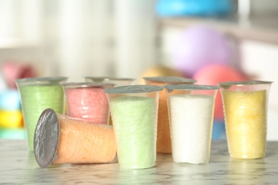 Plastic cups with cotton candy on table against blurred background